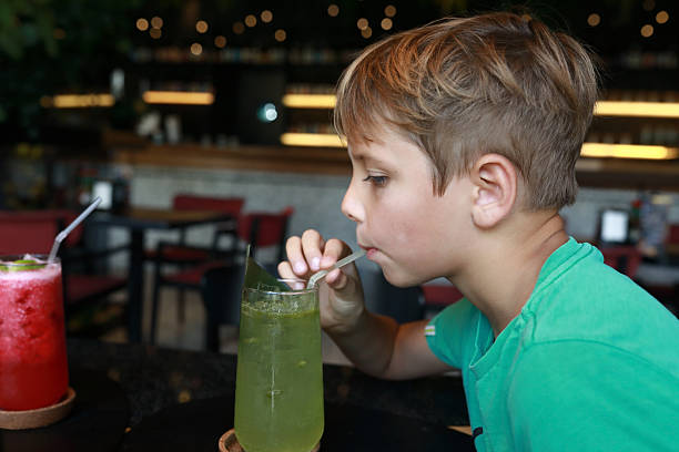 istock Caucasian kid drinking green beverage from glass with straw 2249710137