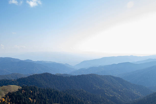 istock Mountain landscape with forested ridges, layered peaks and soft sunlight under clear blue sky with scattered clouds 2249711271