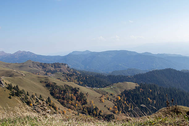 istock Mountain landscape with rocky foreground, grassy slope, forested hills and distant peaks under clear blue sky 2249711279