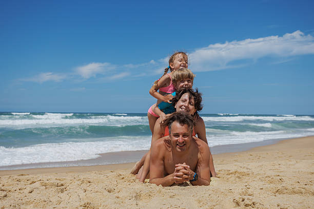 istock Playful family with kids play making human stack on sandy beach 2249712935