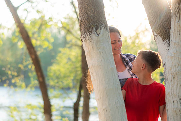 Mother and son smiling, looking at each other, enjoying beautiful natural light outdoors