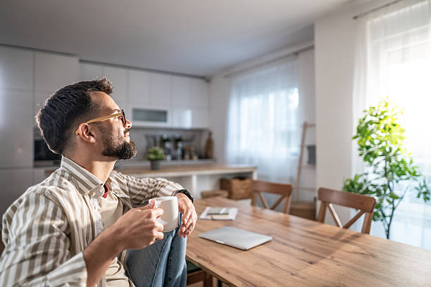 istock Man enjoying coffee looking through window at home 2249713339