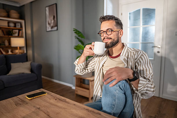 istock Man drinking coffee at home while relaxing in morning sunlight 2249713537