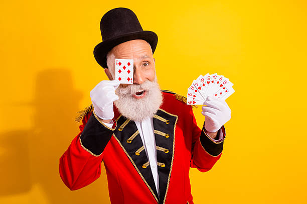 male magician performing a trick with hands isolated on red background, with colourful halloween make-up on face