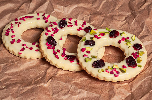 istock Delicious ring cookies with white icing and dried fruit on brown paper 2249719317