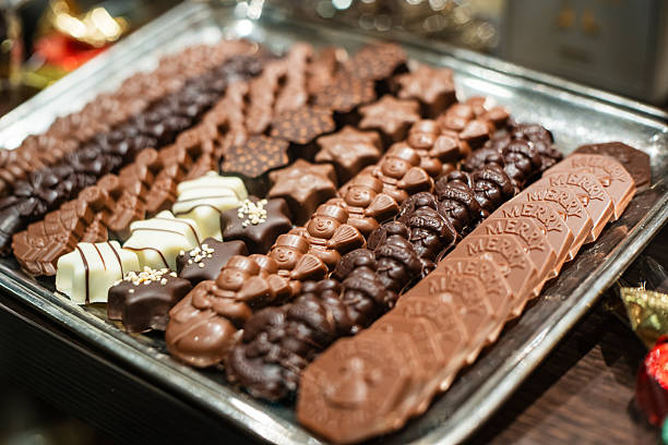 Christmas themed and shaped chocolate assortment on a silver tray inside shop window display. Close up shot, shallow depth if field, no people