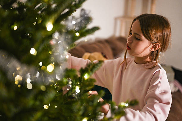 istock Young girl decorating warm christmas tree lights 2249723527