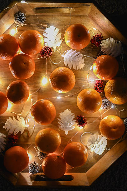 Tangerines, pine cones, and decorative lights arranged on a tray for the winter holiday season