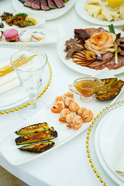 A served festive table with white plates and a cloth napkin. Beautiful serving of dishes at a banquet.