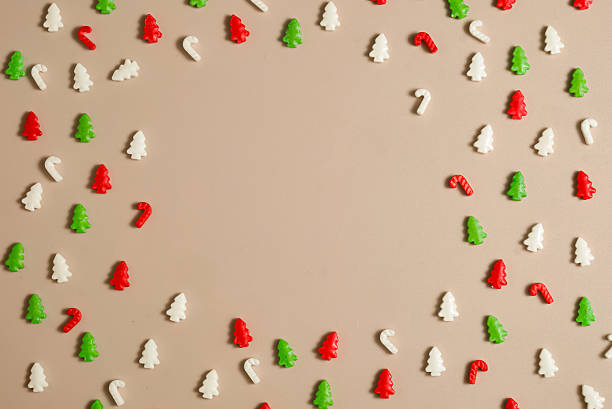 Colorful Christmas candy shapes forming a playful frame on a beige background. Fun full-frame top-view layout ideal for kids themes, festive cards, packaging, and holiday designs. Copy space