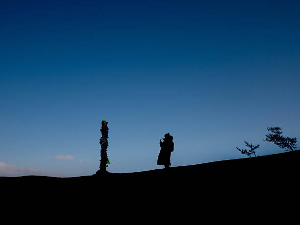 Silhouette of detailed monument statues, including a chariot and figures, standing against a vibrant, cloudy sunset sky in Madrid, Spain, capturing an iconic European landmark at golden hour