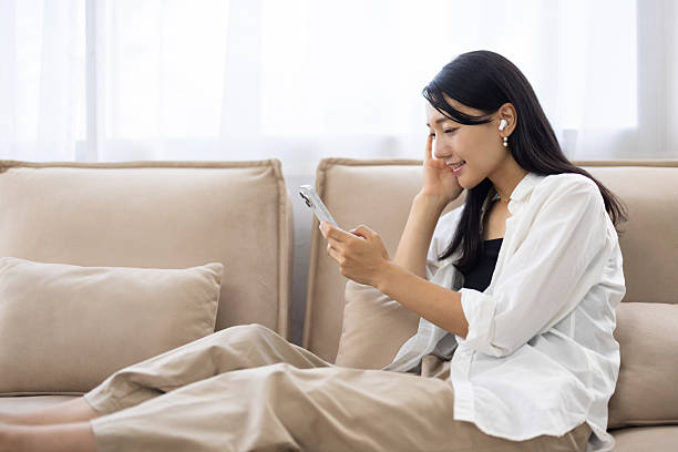 istock Smiling Woman with Wireless Earbuds Looking at Smartphone 2249726059