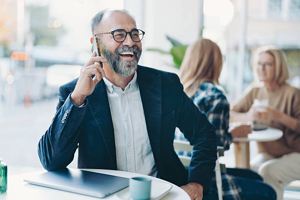 istock Smiling mature businessman talking on the phone in a cafeteria 2249727408