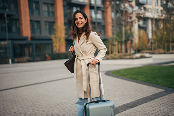 istock Woman traveler smiling pulling suitcase in city 2249729304