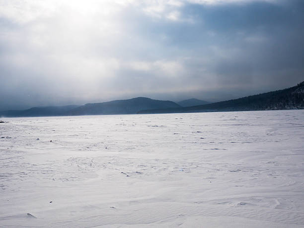 A captivating and peaceful winter scene showcases vast, untouched snow plains gently laid under a cloudy sky