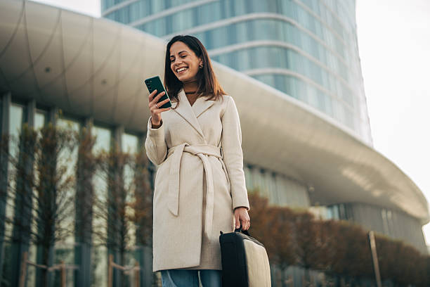 istock Woman checking smartphone laughing downtown carrying briefcase 2249729971