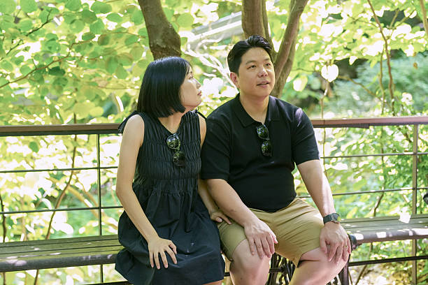 istock A man and woman are sitting on a bench in a park 2249731087