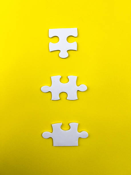 istock A conceptual puzzle photography with interlocking white puzzle pieces, some connected and some isolated, set against a vibrant yellow backdrop. 2249731416