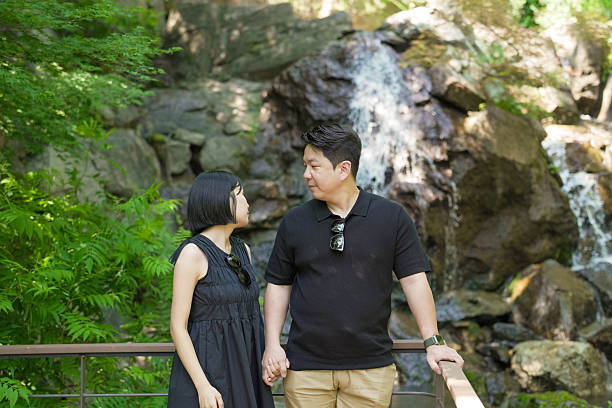 istock A man and a woman are standing next to a waterfall, holding hands 2249733252