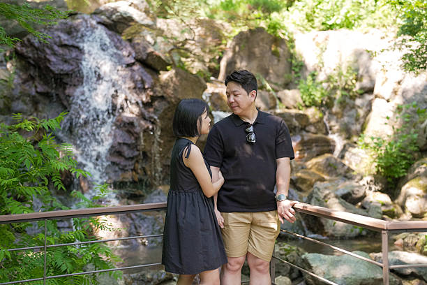 A man and a woman are standing next to a waterfall