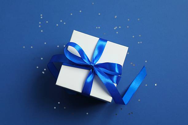 istock Beautiful gift box tied with bow on blue background 2249735097
