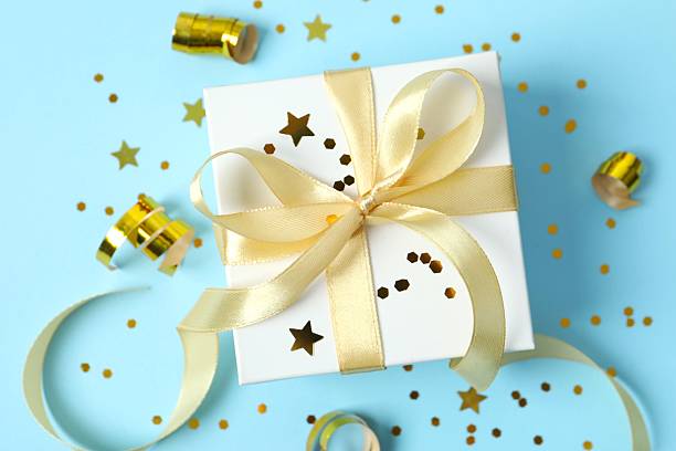 istock Gift box tied with bow and confetti on blue background 2249735133