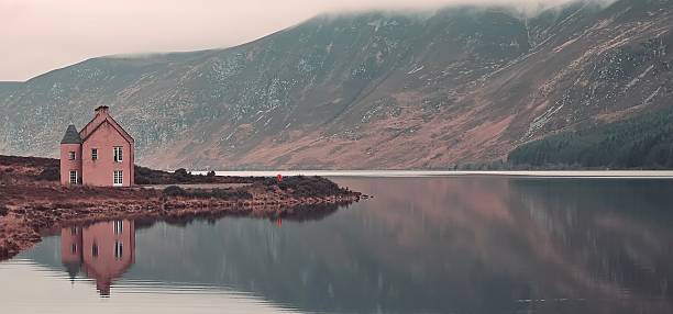 Young hiker with a backpack looking at the Pine Island in Derryclare Lough, Galway county, Ireland