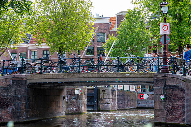 Amsterdam, Netherlands - 45August 2025: Bicycles rest on a bridge overlooking a calm canal with vibrant buildings nearby.
