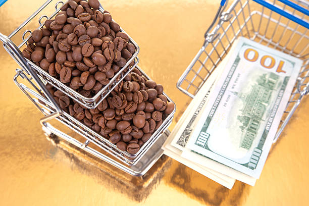 istock Coffee beans overflow a shopping cart alongside $100 bills on a reflective gold surface, ideal for themes of money, trade, and gourmet products 2249740075