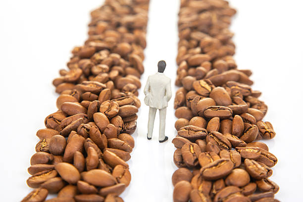 istock Creative stock image of a tiny figure in a suit walking amidst coffee beans, symbolizing a professional journey in coffee commerce 2249741222