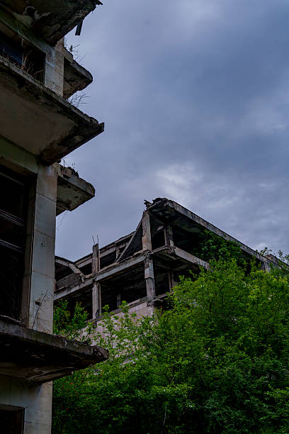 istock Abandoned concrete complex rising above lush green forest canopy 2249741355