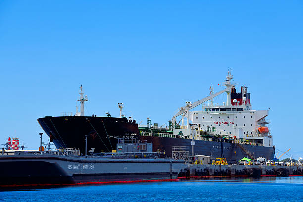 Pearl Harbor, Honolulu, Hawaii, USA: The US-flagged product tanker Empire State moored at Joint Base Pearl Harbor-Hickam. Operated by American Petroleum Tankers and chartered by the Military Sealift Command, this double-hull vessel supports Department of War logistics, including the critical transport of fuel during the Red Hill facility defueling mission. The ship, featuring a black hull and white superstructure, is berthed alongside a US Navy fuel barge, facilitating the transfer of energy supplies essential for Pacific fleet operations. Jones Act Product Tanker (Medium Range) - MT Empire State (T-AOT-5193).