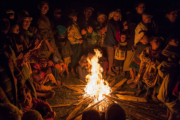 A Hmong village turns out to greet newcomers and warm themselves around a fire.