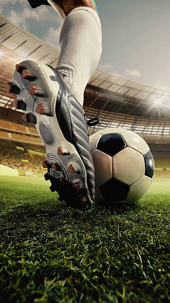 istock Close-up soccer shoe pressing ball with intensity on grass under 3D stadium lights 2249746824
