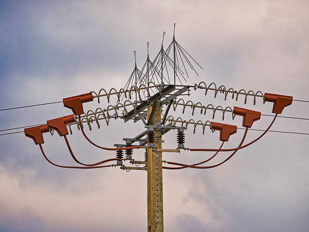 Overhead electricity transmission lines under a cloudy sky at dawn