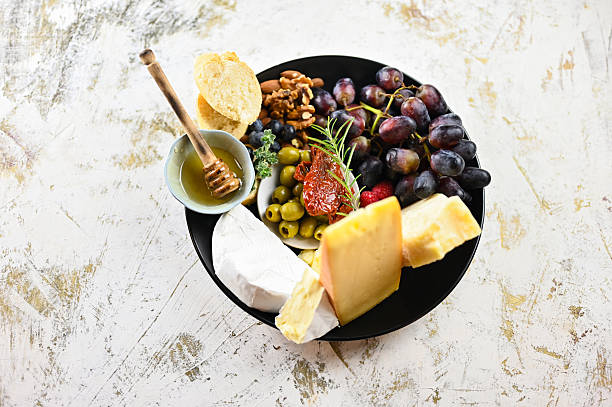 Cheese board presenting a selection of cheeses, grapes, nuts, honey, and olives