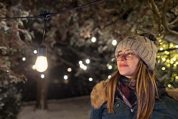 istock Teenager stands under string lights on snowy winter night, framed by glowing bulb and quiet trees 2249755740