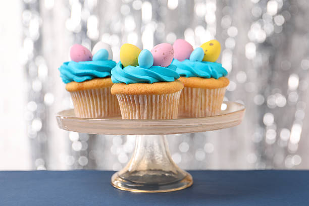 Tasty decorated Easter cupcakes on blue table, closeup