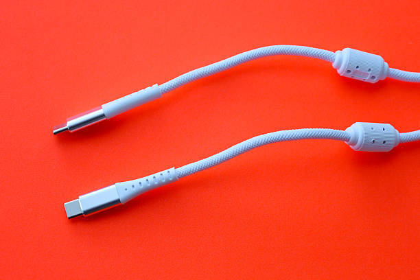 istock A close-up view showing two white USB Type-C cables with protective fabric braiding on a bright orange-red background. 2249758990