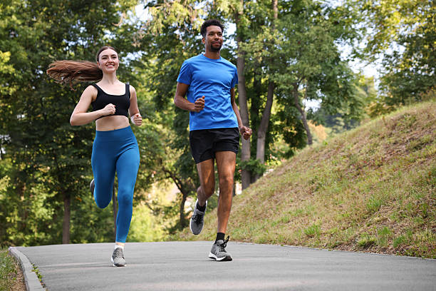 istock Couple in sportswear running in park, low angle view. Space for text 2249763683