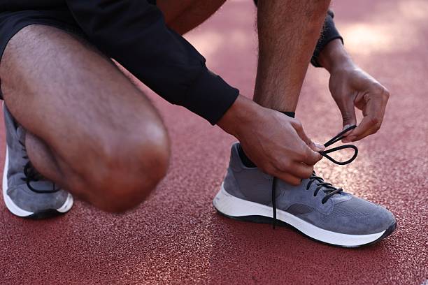 istock Runner tying shoelace of his sneaker at stadium, closeup 2249763740