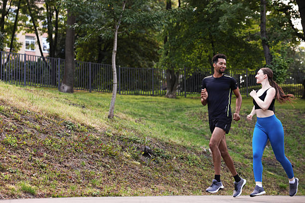istock Couple in sportswear running in park, low angle view. Space for text 2249764474