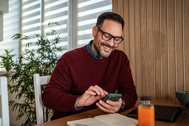 istock Smiling man networking using phone at casual home office 2249766319