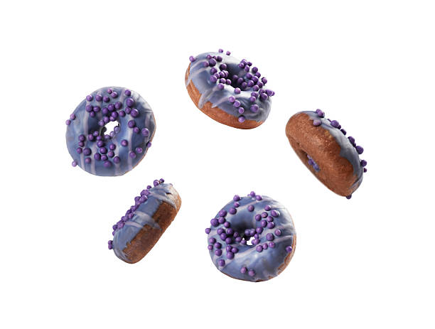 A collection of five purple glazed donuts sits on a white surface. Each donut is topped with tiny purple sprinkles, showing a vibrant and appealing look perfect for dessert lovers.