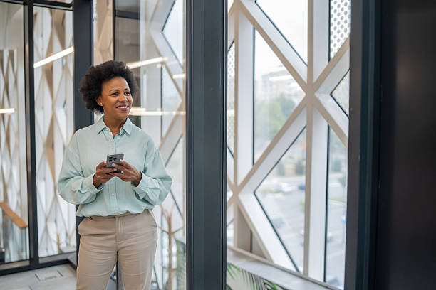 istock Smiling businesswoman using smartphone in modern office building 2249768060
