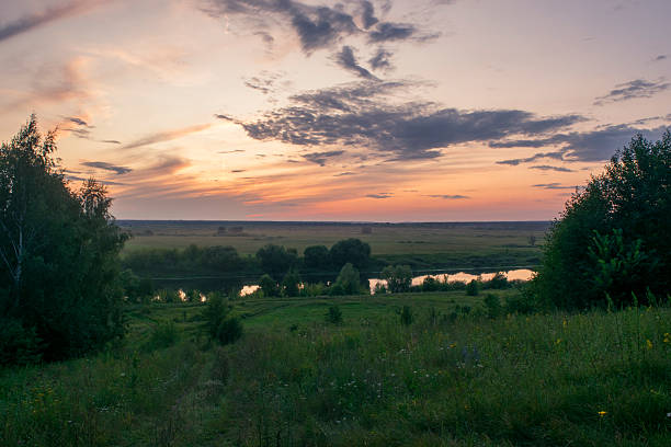 wide horizon with tranquil sunset and reflections, serene dusk over rolling plains with shining pond