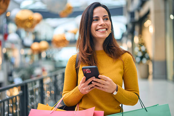 istock Happy woman shopping in mall using phone 2249771534
