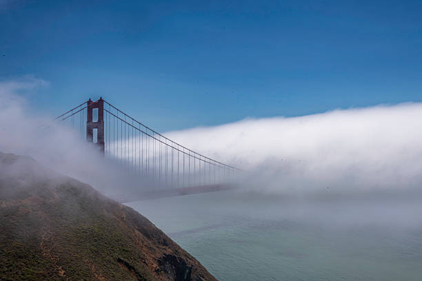 The Golden Gate Bridge shrouded in fog is a sight that evokes a sense of mystery and timeless beauty. The iconic structure, normally bathed in sunlight, becomes almost ethereal when enveloped in a thick fog that create a feeling of solitude and isolation, as if the bridge were a solitary sentinel guarding the entrance to the bay