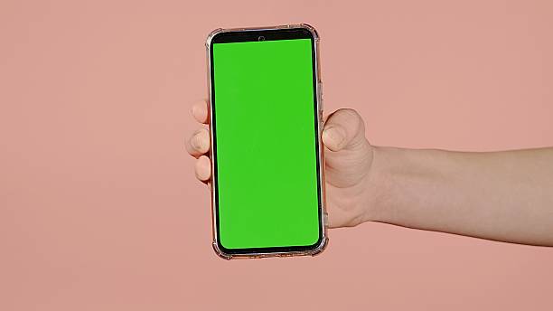istock Female hand holding a mobile phone on a pink background with soap bubbles 2249782094