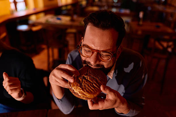 istock Man enjoying eating a large burger in a restaurant 2249784999